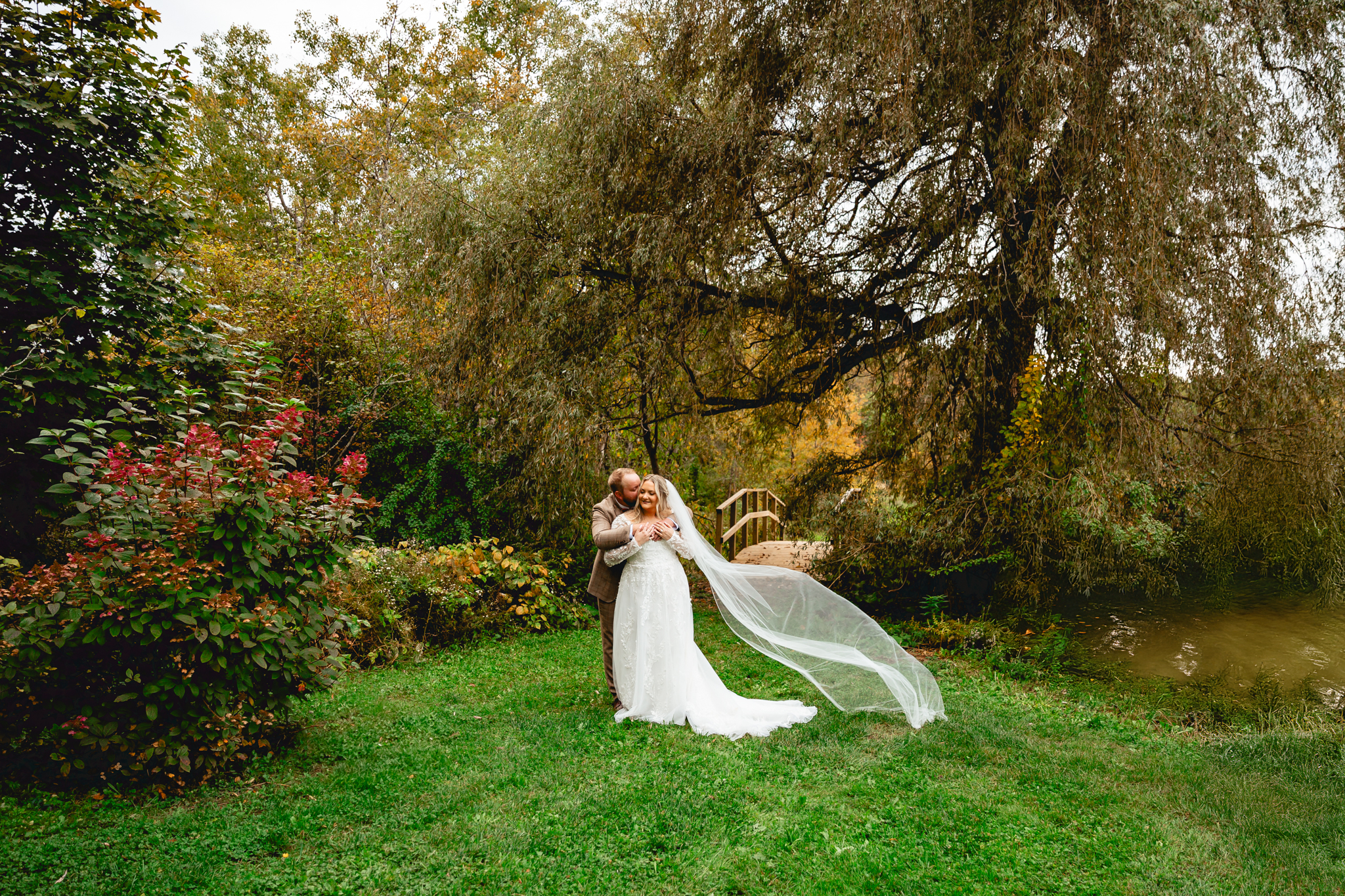 Real wedding couple under the willow tree next to the pond at Meadow Ridge Farm, the best barn wedding venue in Maine